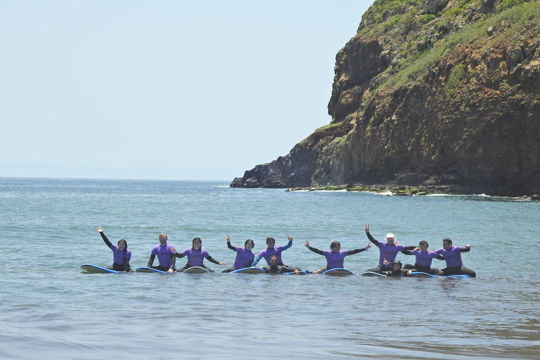 A group of happy surfers during a surf lesson with their rented surfboards in madeira