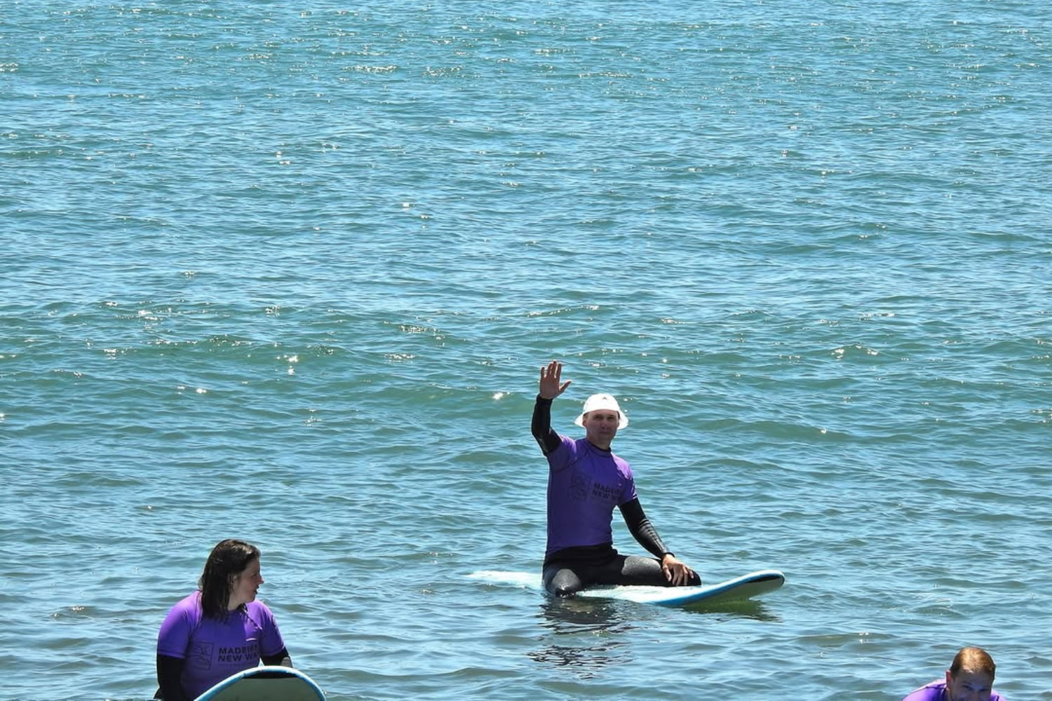 A group of surfers in the middle of the sea during their group surf lessons in madeira