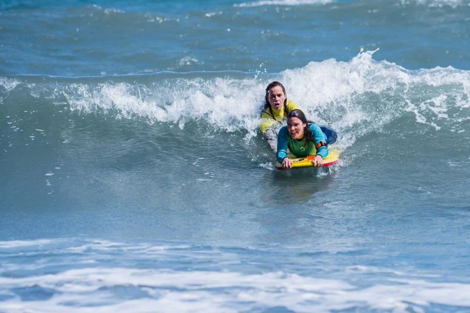 Beginner doing a group bodyboard lesson in madeira with the help of her instructor