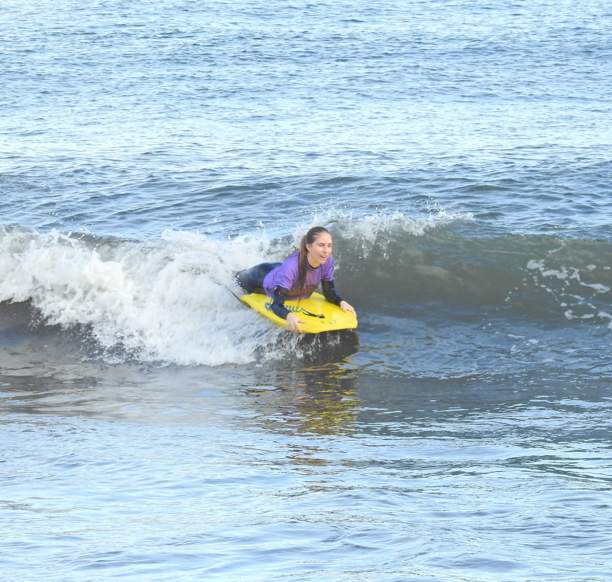 Female riding a wave while doing a group bodyboard lesson in madeira