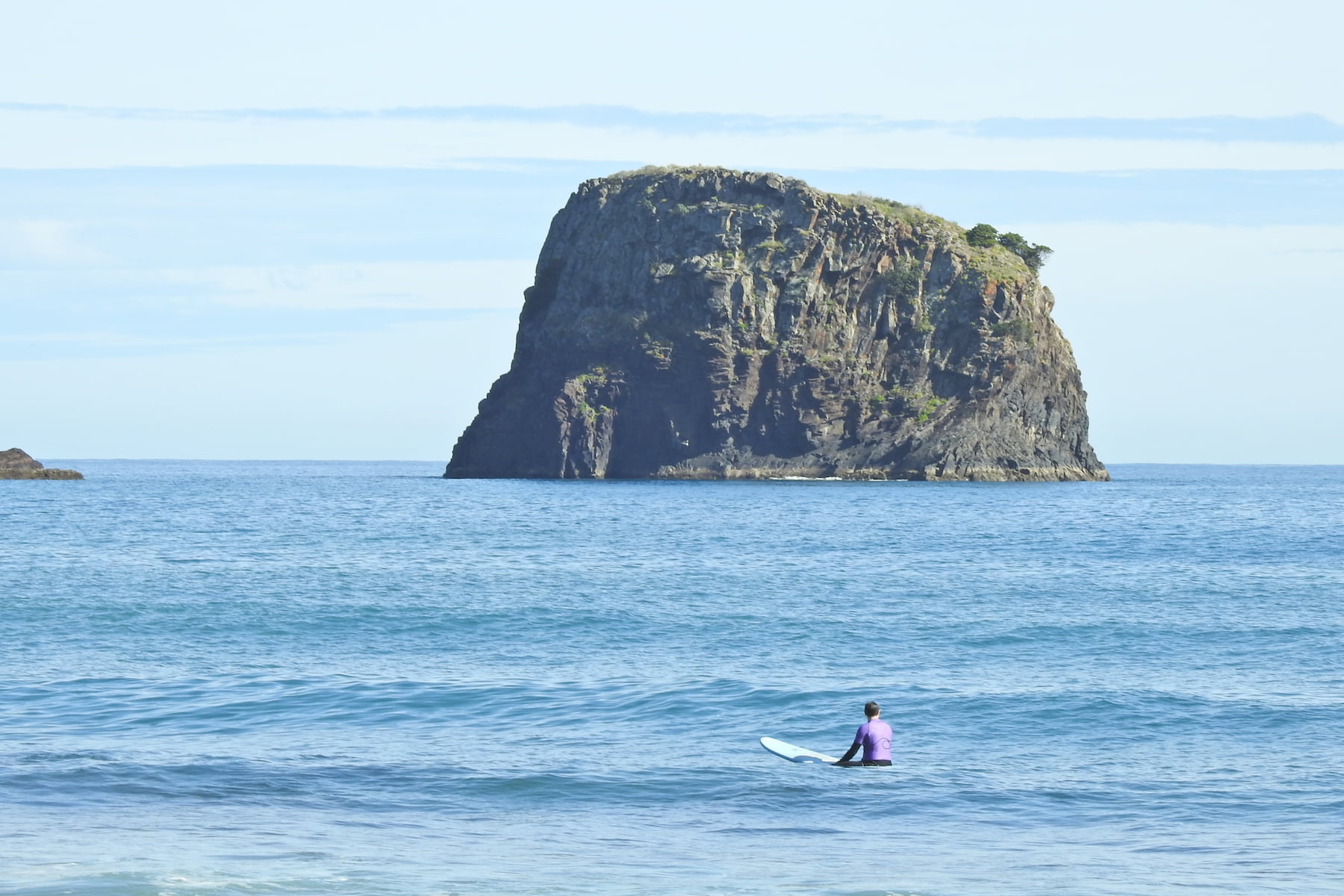 Surfer in the middle of the ocean in Porto da Cruz during his surf lesson in madeira