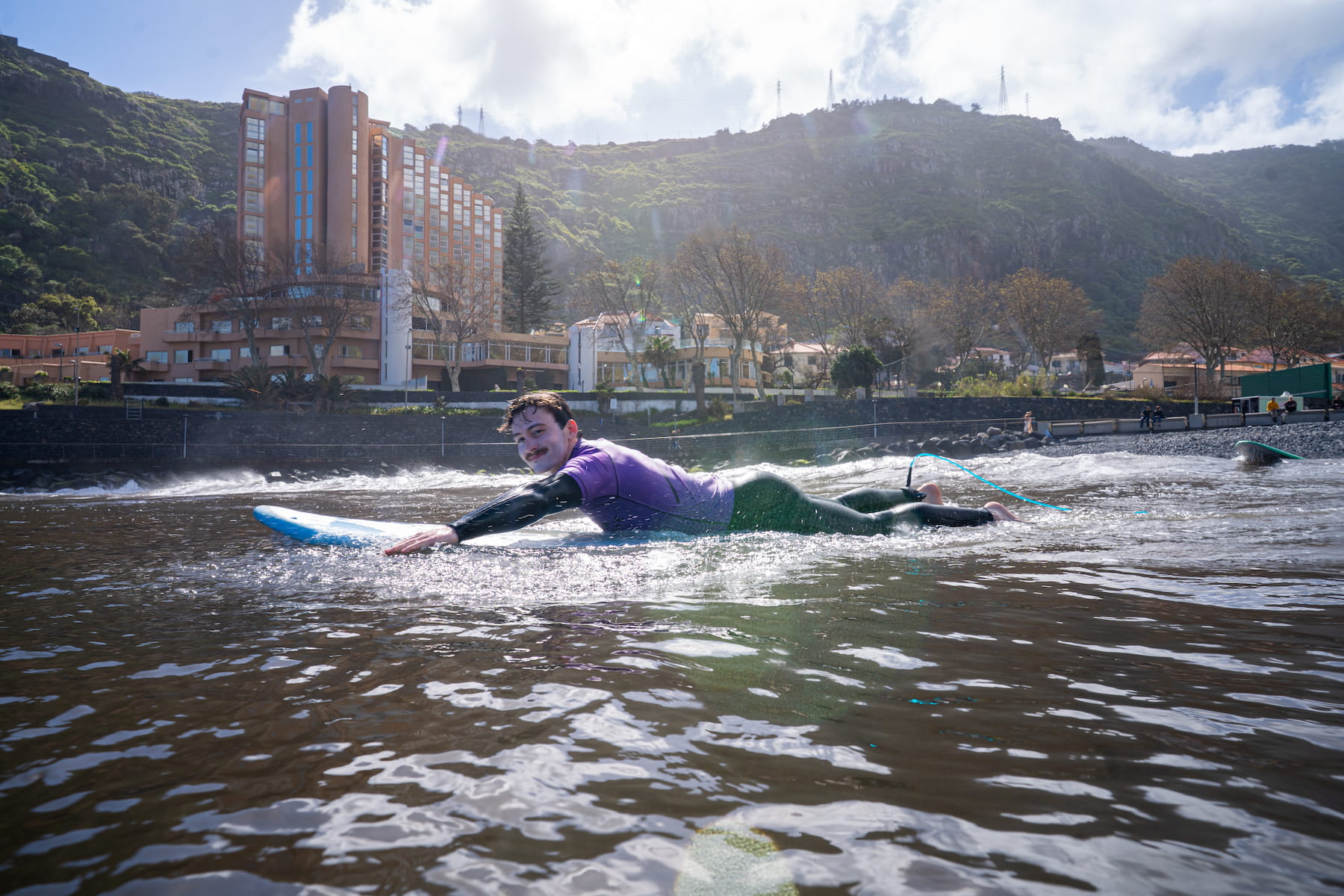 A happy male surfer in his surfboard while doing group surf lessons in madeira