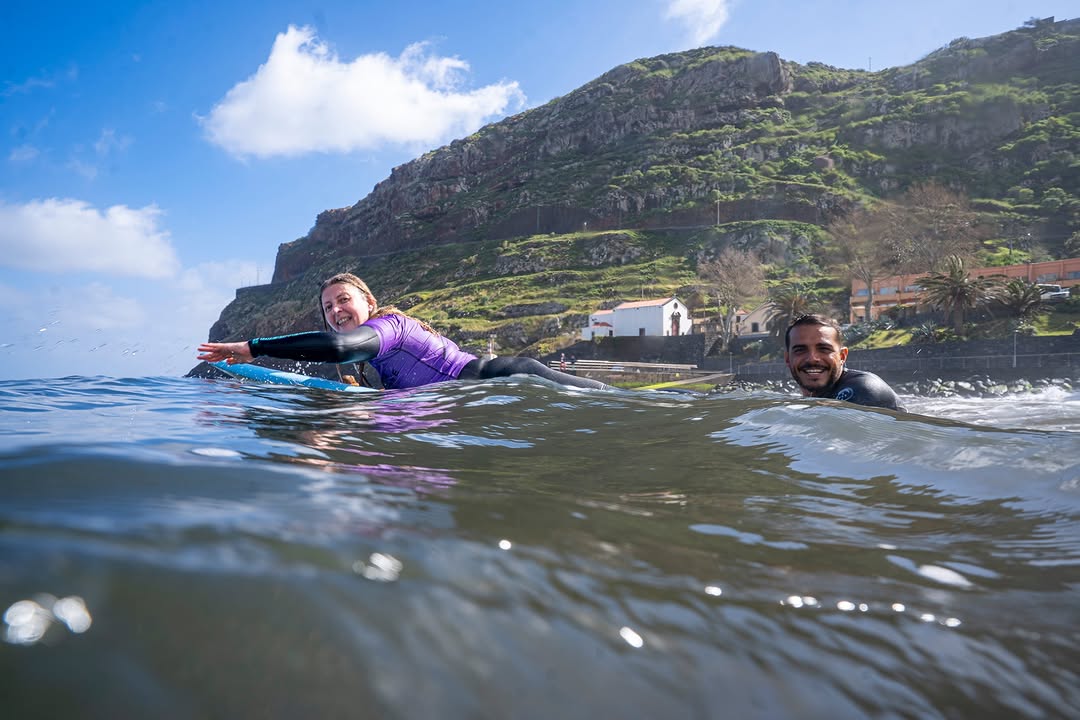 Beginner surfer in the water with her surf instructor doing a private surf lesson in madeira