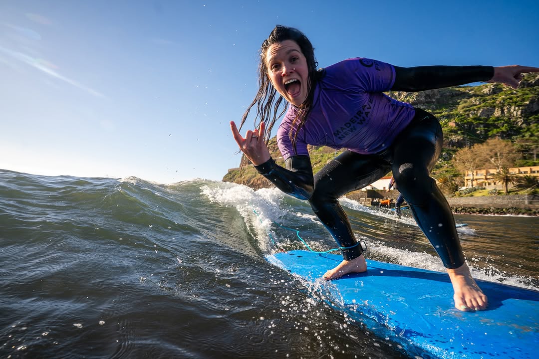 Female surfer happy while riding a wave with a rented surfboard in Madeira