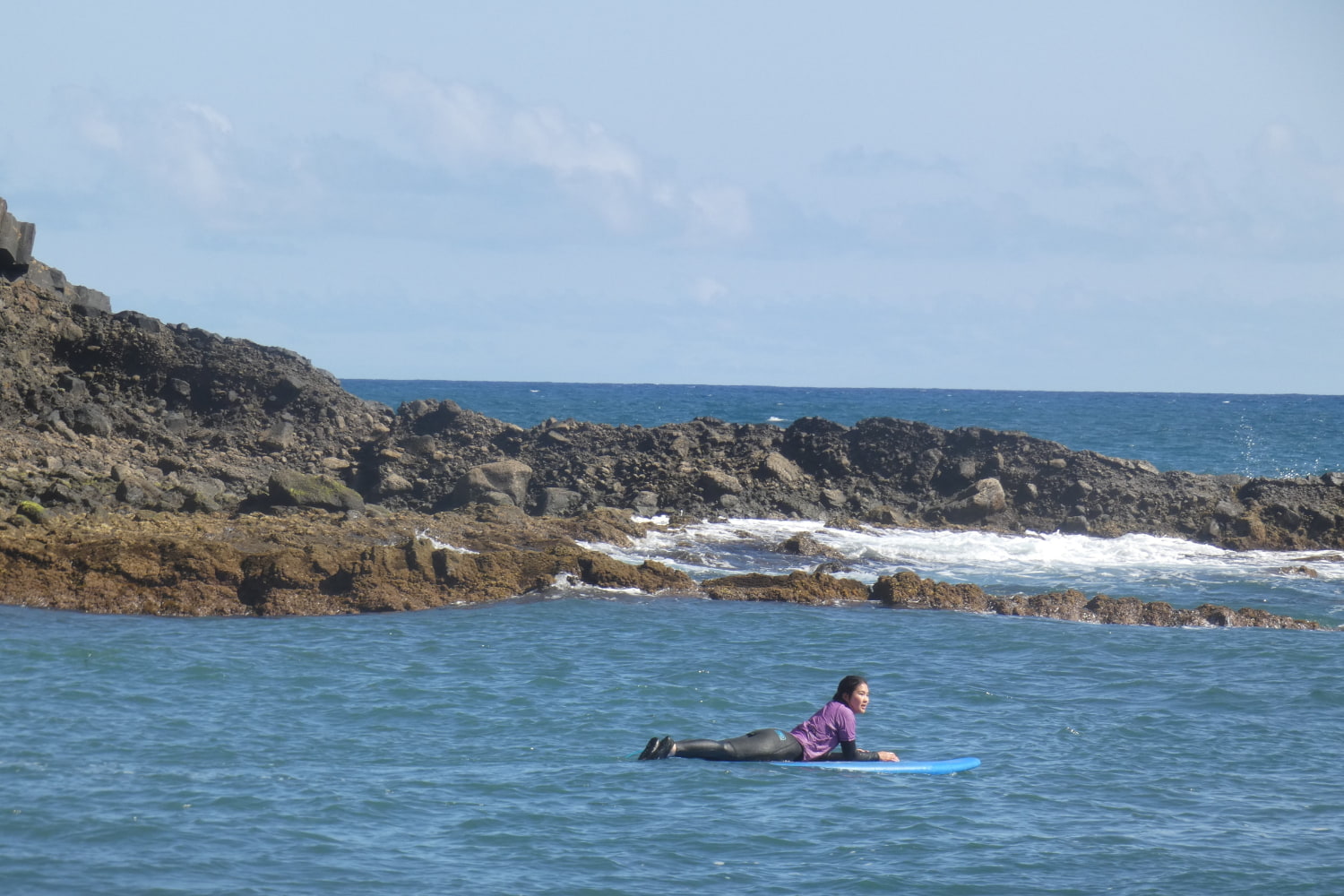 Female surfer laying in her surfboard while doing a surf lesson in Porto da Cruz