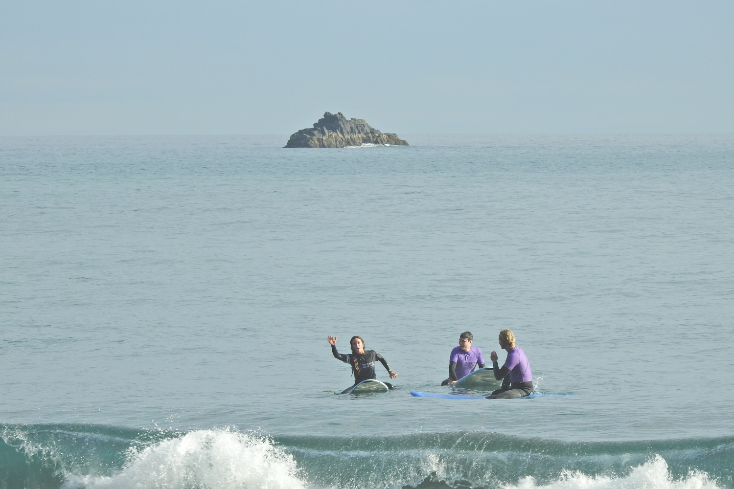 A small group of surfers in Porto da Cruz beach with their surf instructor while doing a private surf lesson in madeira