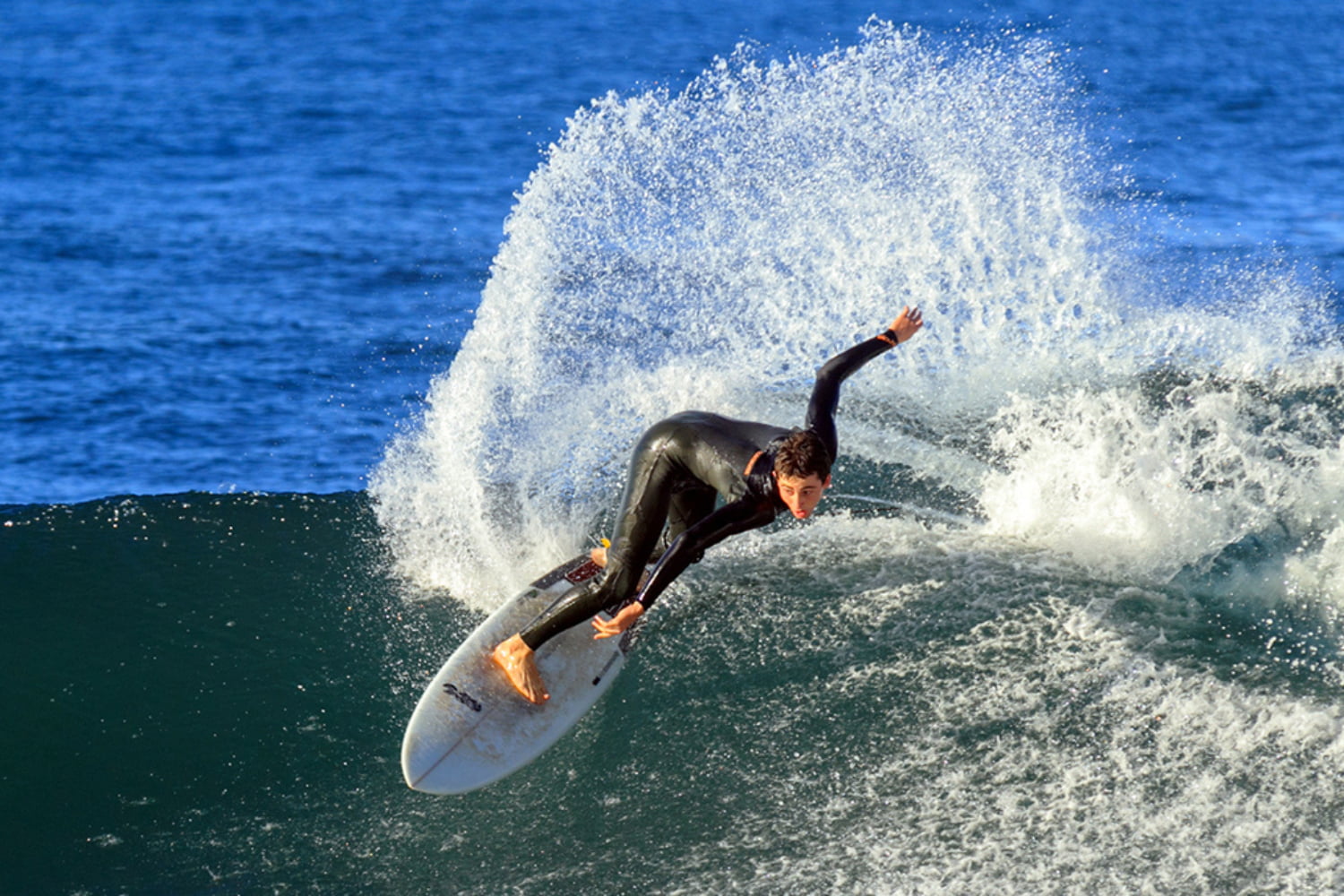 Experienced surfer riding a wave and splashing water while using his shortboard rented in madeira