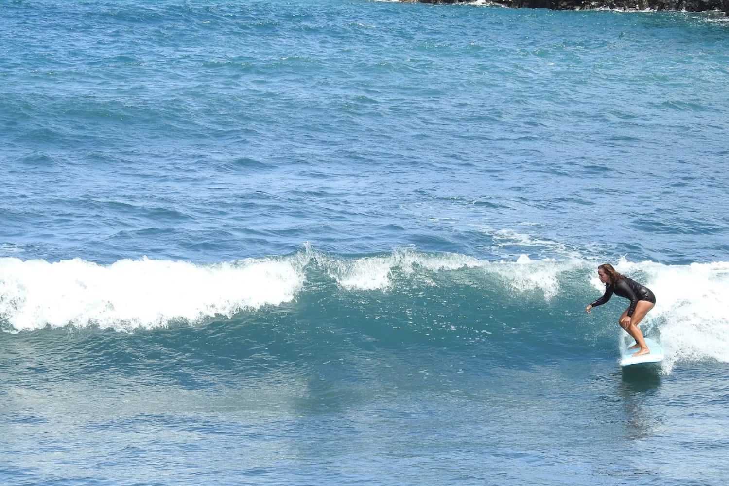 Female surfer riding a wave while using a rented summer wetsuit in madeira