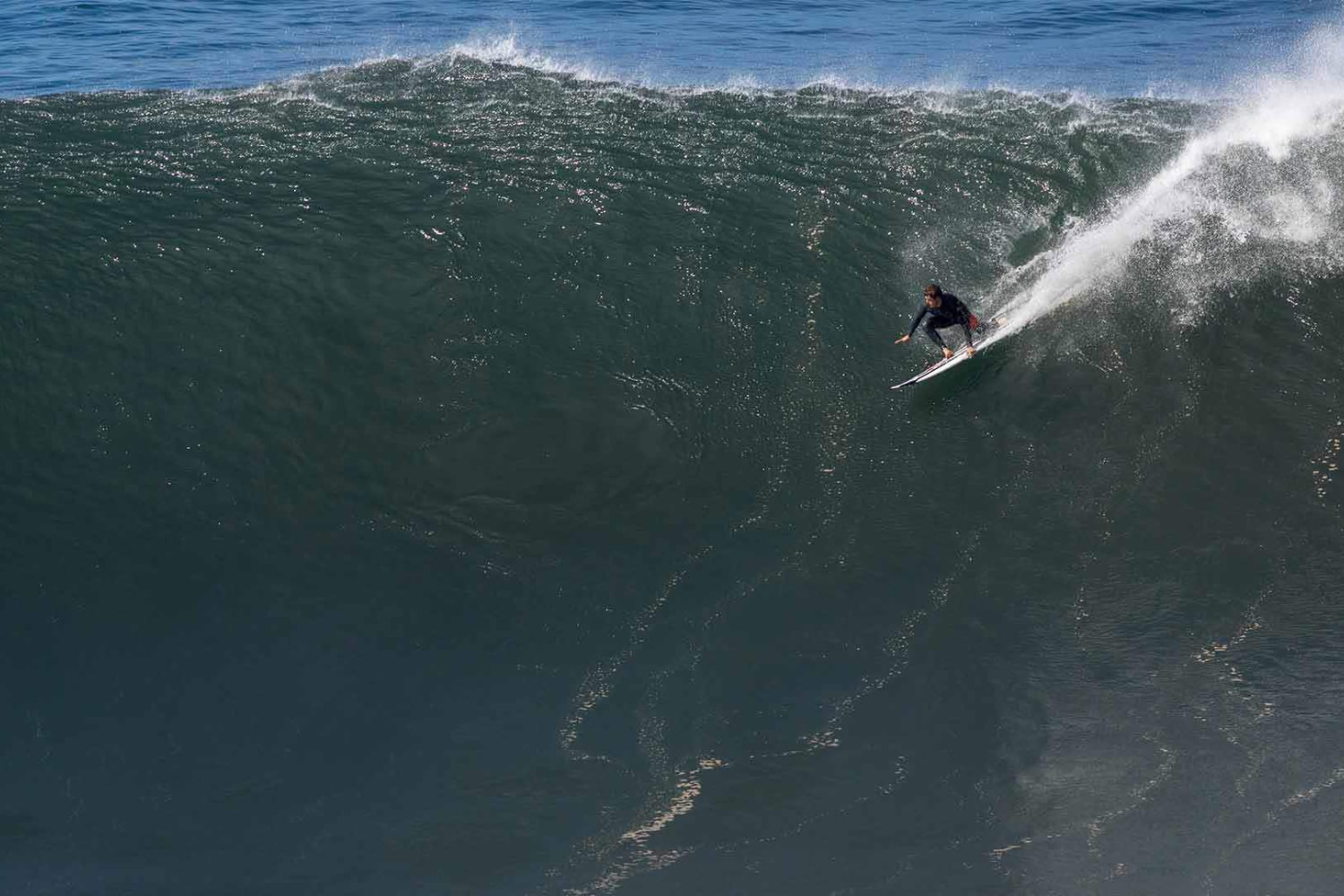 Massive wave in Jardim do mar with a surfer riding it after the advice from the surf guide in madeira