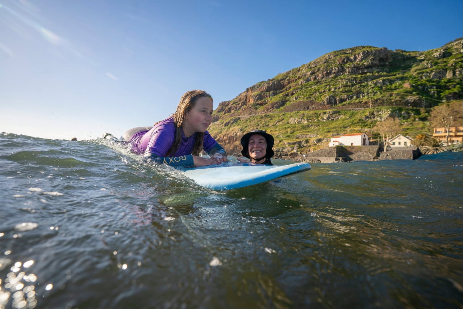 Young kid doing a surf lesson for kids in madeira with her surf instructor