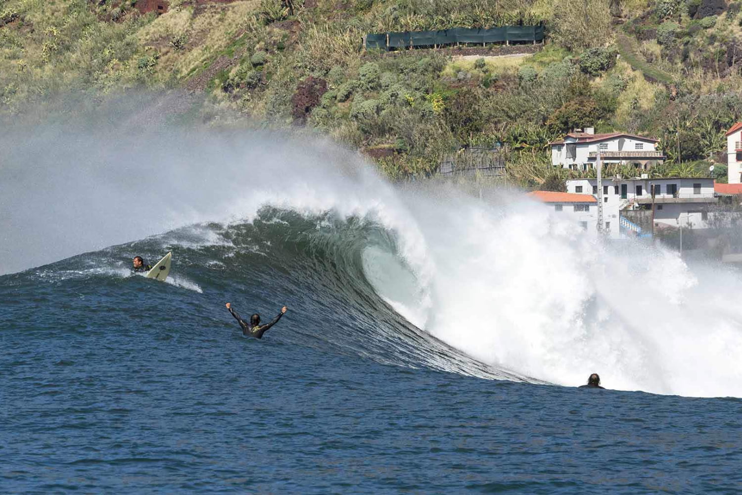 Surfers riding a big wave in a surf spot in paul do mar chosen by a surf guide in madeira